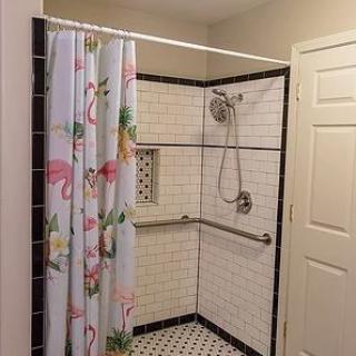 A bathroom with a shower area featuring a floral-patterned curtain and white tiled walls.