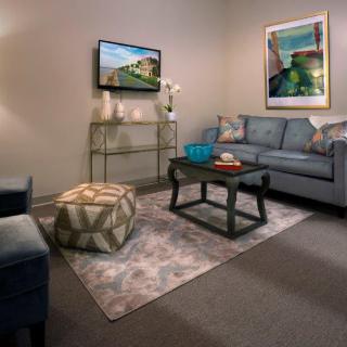 A cozy living room with a comfortable sofa, decorative artwork, and a television mounted on the wall.