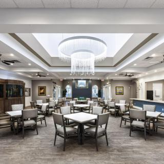 A modern dining room with neatly arranged tables and chairs under elegant ceiling lights.