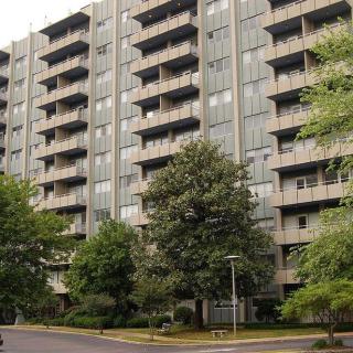 A residential apartment building with multiple balconies surrounded by trees.