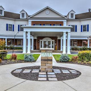 A symmetrical two-story building with columns at the entrance and well-maintained landscaping.