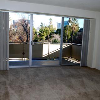 A spacious living room featuring sliding doors that open to a balcony, with plenty of natural light filtering in.