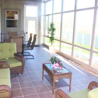 A bright sunroom with comfortable seating and large glass windows, filled with natural light.