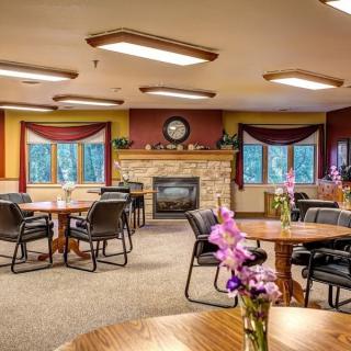 A cozy dining room with a fireplace, neatly arranged tables and chairs, and floral decorations.