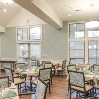 A well-lit dining room with neatly arranged tables and chairs.