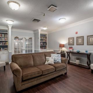 A cozy living room with a brown sofa, bookshelves, and warm lighting.
