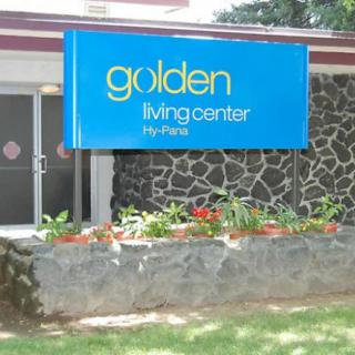 The entrance of a healthcare facility with a sign for Golden Living Center, featuring a small garden area.
