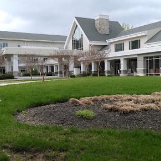 A modern building with a landscaped lawn and cloudy sky.