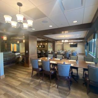 A modern dining area with elegant chandeliers, wood flooring, and neatly arranged tables and chairs.