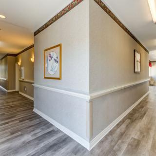 A modern hallway with artwork, wooden flooring, and soft lighting.