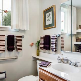 A cozy bathroom with striped towels, a large mirror, and decorative elements.