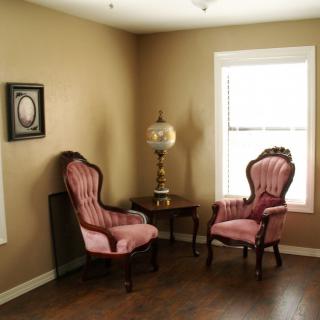 A cozy corner with vintage chairs and an antique lamp beside a window.