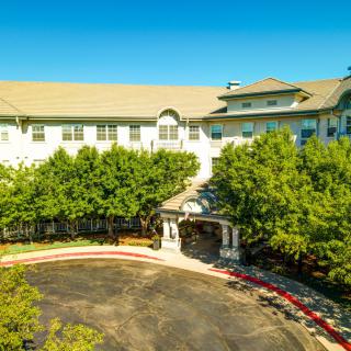 Aerial view of a hotel entrance surrounded by trees and landscaping.
