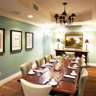 An elegant dining room with a long table set for a meal, decorated with artwork and a chandelier.