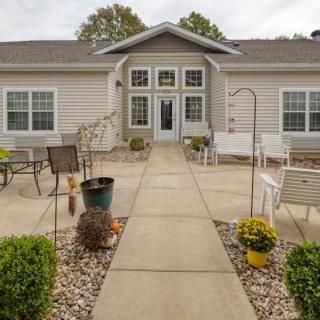 A cozy house with a well-maintained patio featuring outdoor furniture, plants, and a pathway.