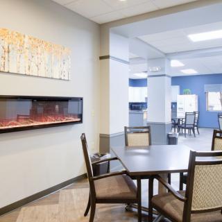 A modern dining area featuring tables, chairs, and a wall-mounted fireplace.