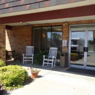 An entrance with two rocking chairs, potted plants, and glass doors.