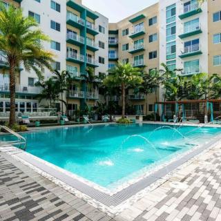 Modern apartment complex with a swimming pool and palm trees.