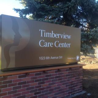 A sign for Timberview Care Center with a brick base outdoors.