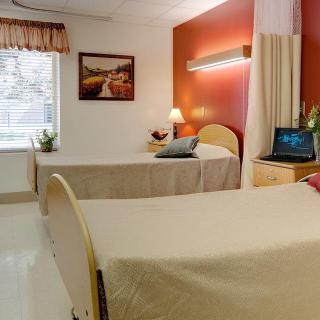 A clean and organized hospital room with two beds and a window.