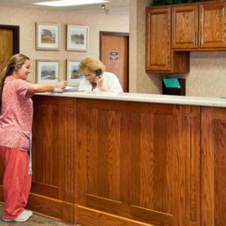 A receptionist assists a visitor at the front desk.
