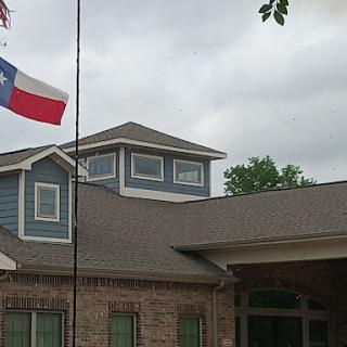 A Texas flag flies in front of a building under a cloudy sky.