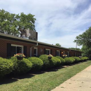 A well-kept residential building surrounded by neatly trimmed bushes under a clear blue sky.