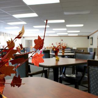 A well-lit dining area adorned with autumn-themed decor, featuring tables and chairs arranged for a welcoming atmosphere.