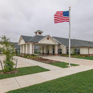 A welcoming building adorned with the American flag, set against a grassy landscape.