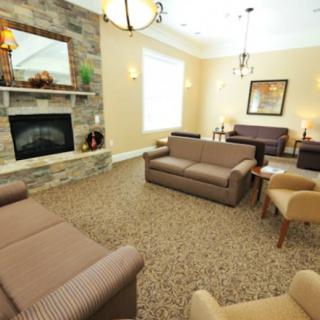 A cozy living room with a fireplace, multiple sofas, and armchairs arranged on a carpeted floor.