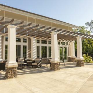 A sunny outdoor patio featuring a pergola and comfortable seating area.