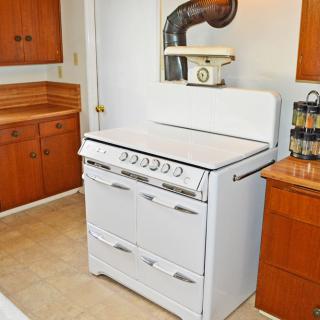 A retro kitchen with a vintage white stove featuring classic knobs and wooden cabinets.