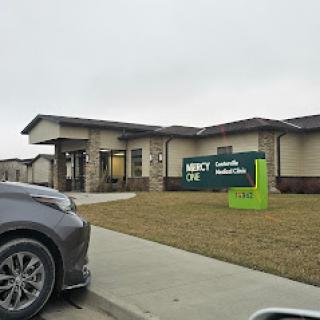 A healthcare facility featuring a prominent sign, viewed from a parking lot under a cloudy sky.