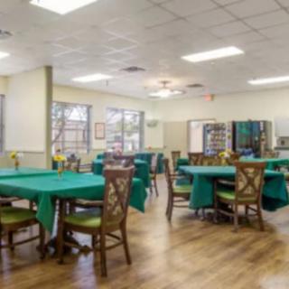 A spacious dining area with multiple tables and chairs, featuring green tablecloths.
