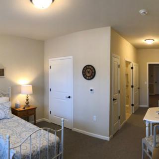 A cozy bedroom with a bed, side table with lamp, and decorative wall items.