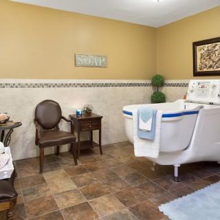 A well-decorated bathroom featuring a white bathtub, elegant chair, and stylish decor.