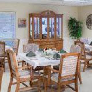 A well-decorated dining room with wooden furniture, including a table set and a glass cabinet.