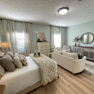 A modern and cozy bedroom with neutral tones, featuring a comfortable bed, elegant furniture, and soft lighting.