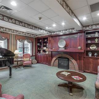 A traditional-style living room with a piano, fireplace, and bookshelves.