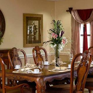 An elegantly decorated dining room featuring a wooden table set with cups and a floral centerpiece.