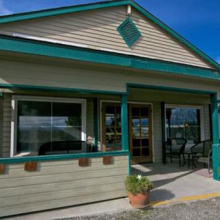 A small building with a porch and large windows under a clear blue sky.
