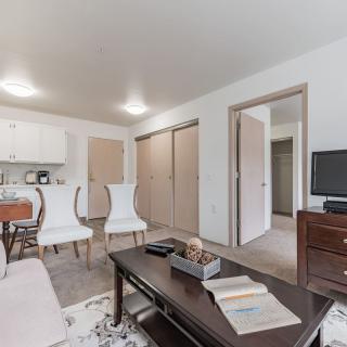 A cozy apartment living space with a kitchenette, featuring classic furniture and a television.