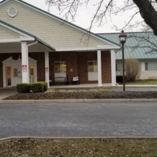 A brick building with white columns at the entrance, viewed from across a road.