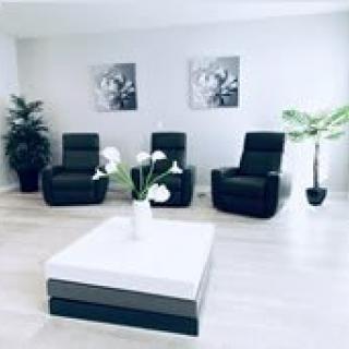 A modern minimalist living room with black chairs, a white coffee table, and indoor plants.