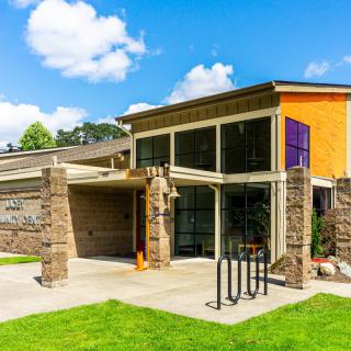 A modern building with stone columns and large glass windows on a sunny day.