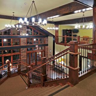 Spacious interior with wooden staircase and chandeliers.