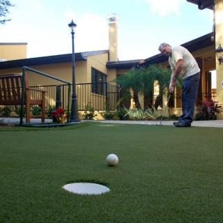 A senior person putting on an outdoor golf green.