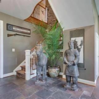 A stylish foyer featuring a staircase, decorative statues, and a large potted plant.