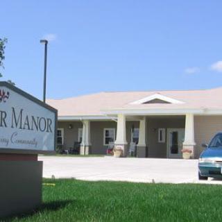 A single-story building with a sign in the foreground and a car parked in front.