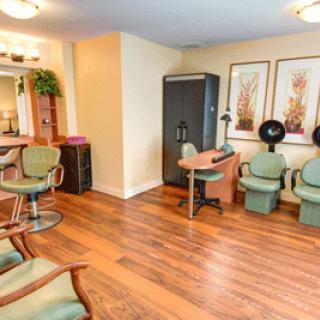 A cozy hair salon interior featuring wooden floors, comfortable chairs, and modern equipment.